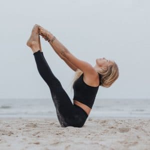 Los beneficios del yoga para cuerpo y mente. Mujer haciendo yoga en la playa